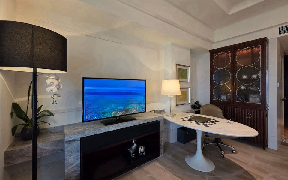 A hotel room with a television on a media console