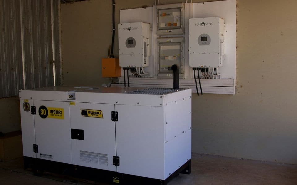 A standby backup generator with inverters mounted on the wall behind it